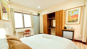 Een hotelkamer met een bed, een bureau, een stoel en een kleine televisie.