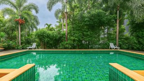 A rectangular swimming pool with green tiles, surrounded by lush greenery and palm trees. - 1BR Near Naiharn Pool&Relaxed Vibes C199 (Rawai)