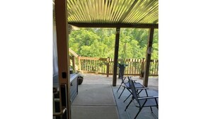 An outdoor patio area with a covered seating area, a grill, and a view of a wooded area. - Quiet, Roomy,  Private Studio,  Beautiful view. (Independence)