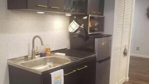 A compact kitchen with dark cabinetry, a stainless steel sink, and a refrigerator. - Quiet, Roomy,  Private Studio,  Beautiful view. (Independence)