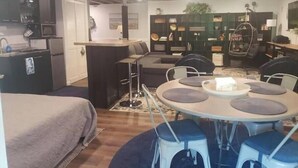A compact living space with a kitchenette, a dining area with a round table and stools, a sofa, and a hanging chair. - Quiet, Roomy,  Private Studio,  Beautiful view. (Independence)
