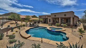 A swimming pool with a wavy design, surrounded by a landscaped garden with cacti and small plants.