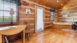 A wooden cabin interior with a desk, chair, and a bathtub. - 21 Acre Mountain Escape!  11 Private Cabins!  Weddings, Reunions, & Events! (Fancy Gap)