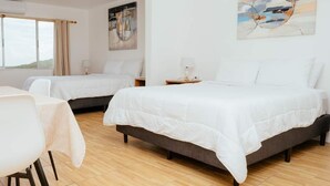 Une chambre d’hôtel avec deux lits, un coin repas et un tableau au mur.