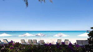 A beach with white umbrellas and lounge chairs. - One Old Trees | Beach Front - Located in  Beautiful Saint James with Private Pool (Saint James)