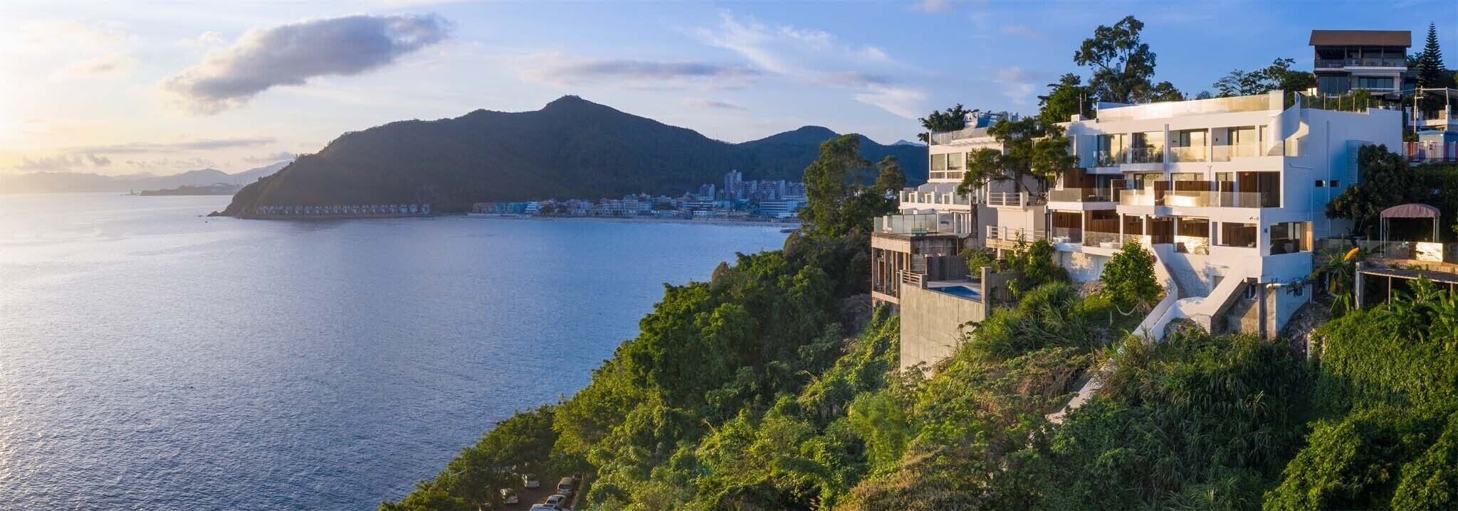Vista costera con edificios modernos, cielo despejado y mar tranquilo.