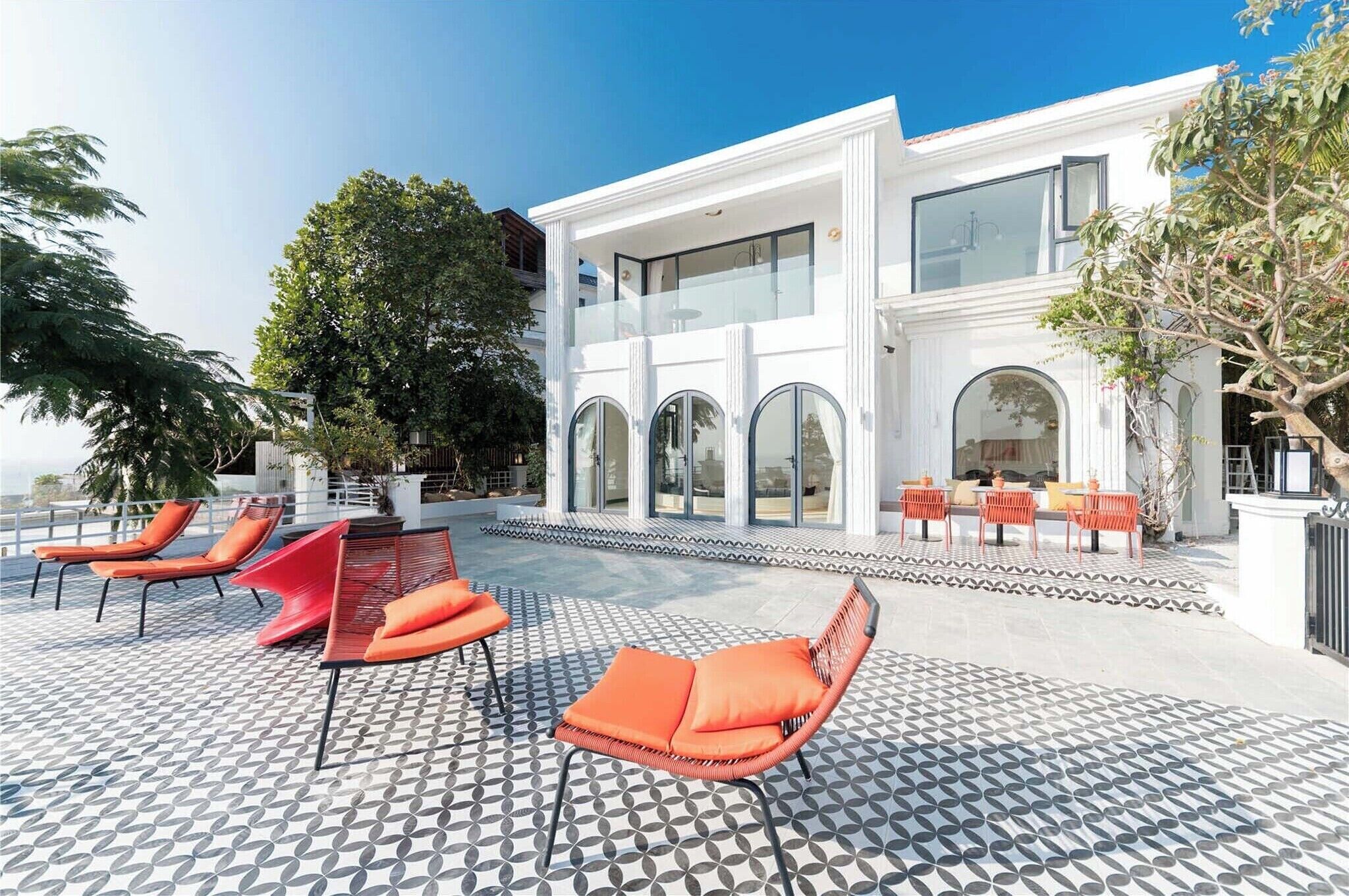 A modern building with a balcony, outdoor seating, and large windows.