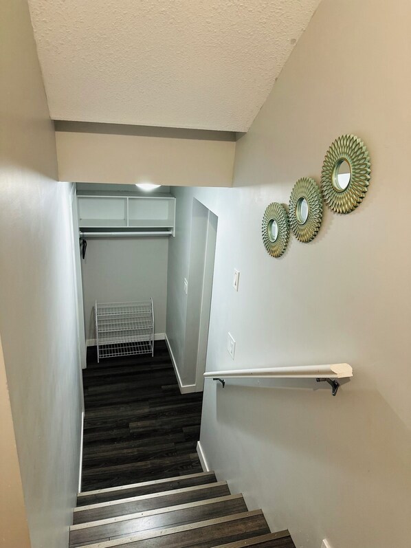 A staircase with dark wood steps and white walls. There are three decorative mirrors on the wall.