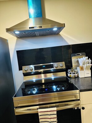 Een keuken met een roestvrijstalen fornuis, oven en afzuigkap.