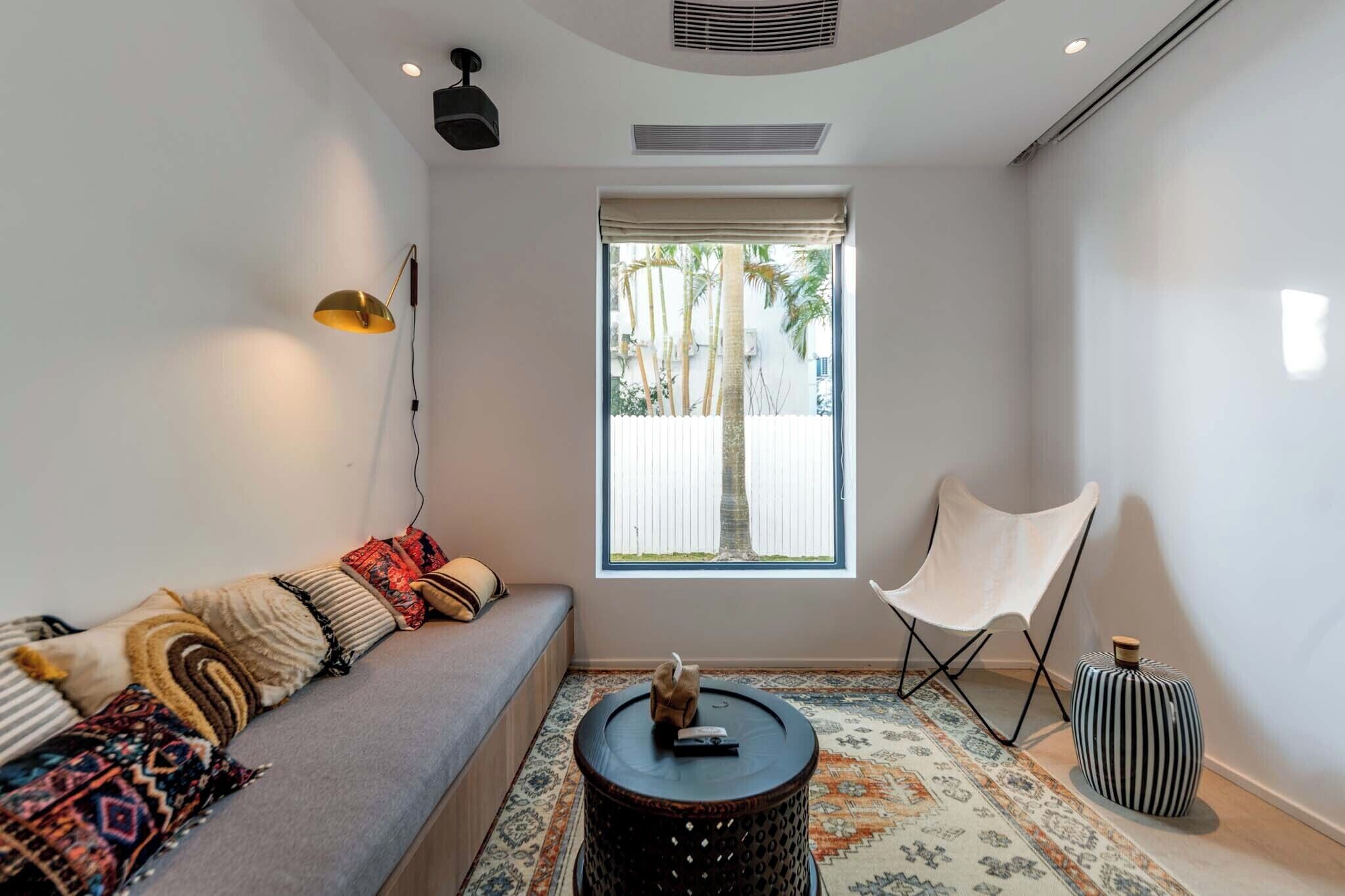 Una sala de estar moderna con un sofá, un sillón, una mesita y una ventana con vistas a palmeras.