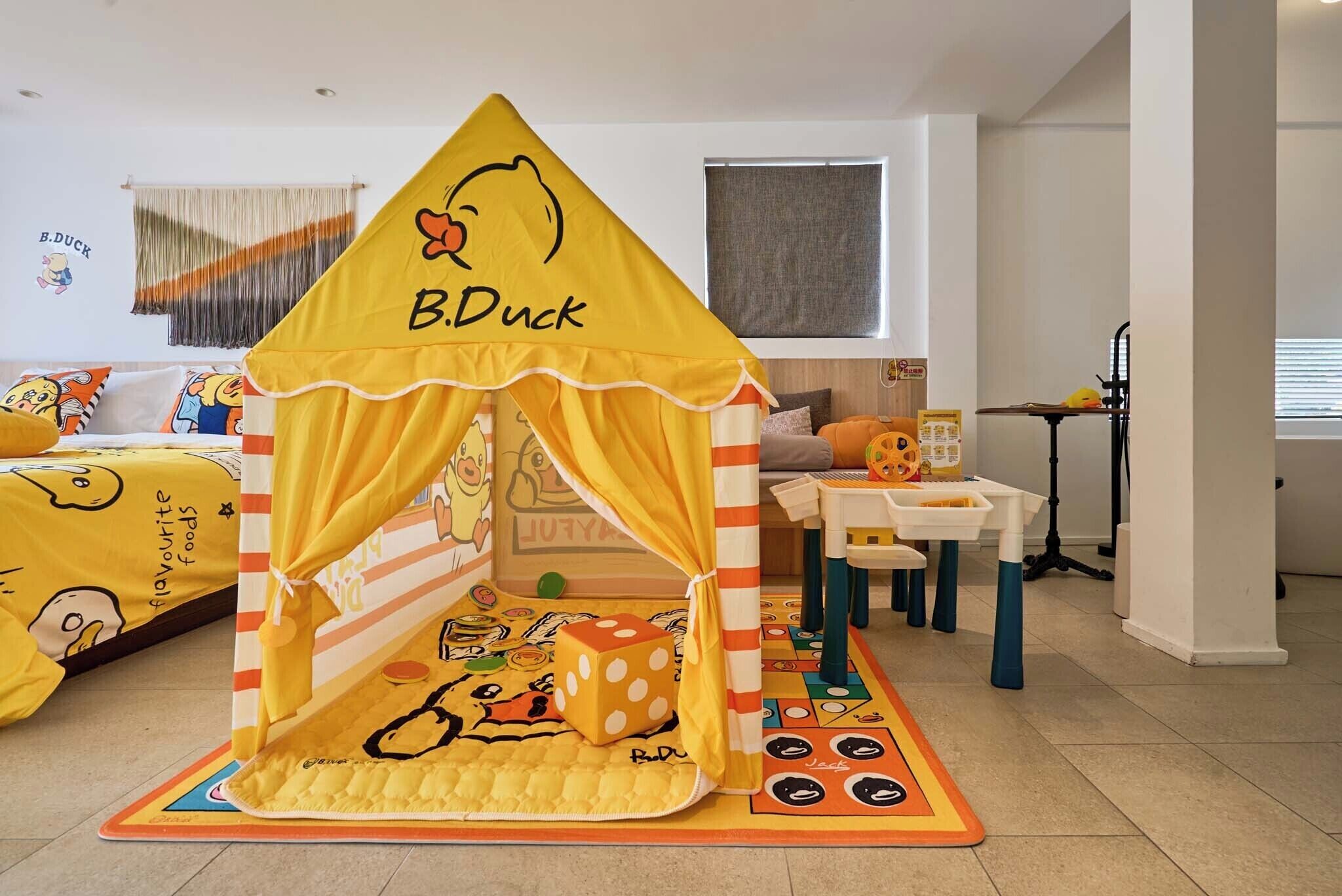 Una carpa de juegos con la marca 'B.Duck', un tapete de juego con diseño de pato y una cama con ropa de cama temática de patos en una habitación.