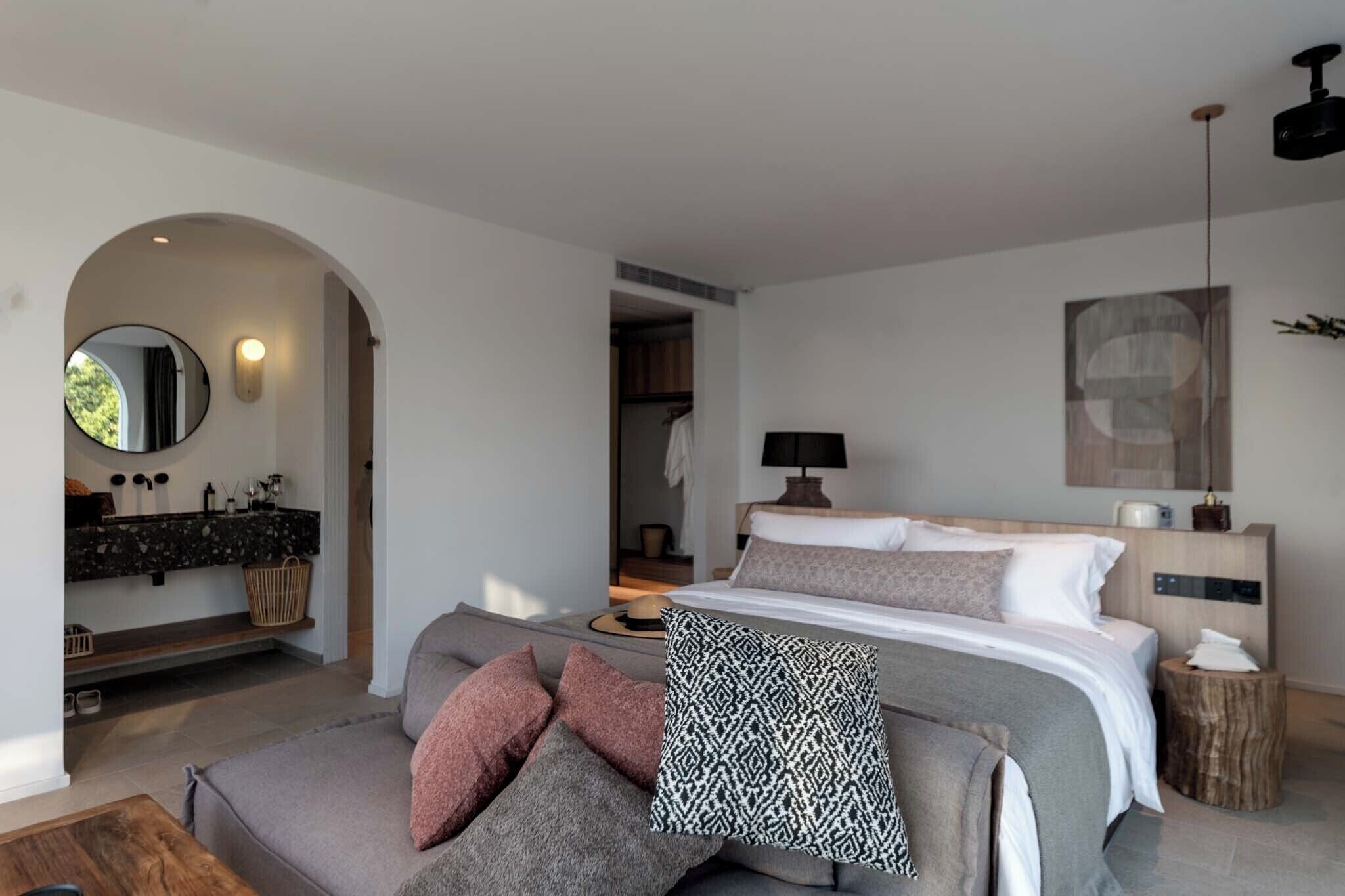 Un dormitorio moderno con una cama grande, un sofá, un tocador con espejo y un cabecero de madera.
