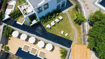Vista aérea de un hotel con piscina en la azotea, zona de estar al aire libre y césped cuidado.