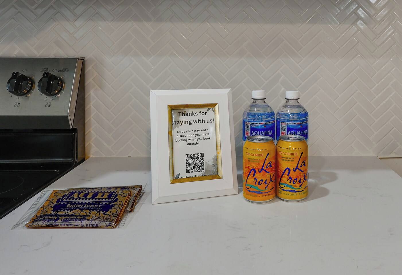 Un comptoir de cuisine avec un cadre décoratif, deux canettes de La Croix et un paquet de beurre.