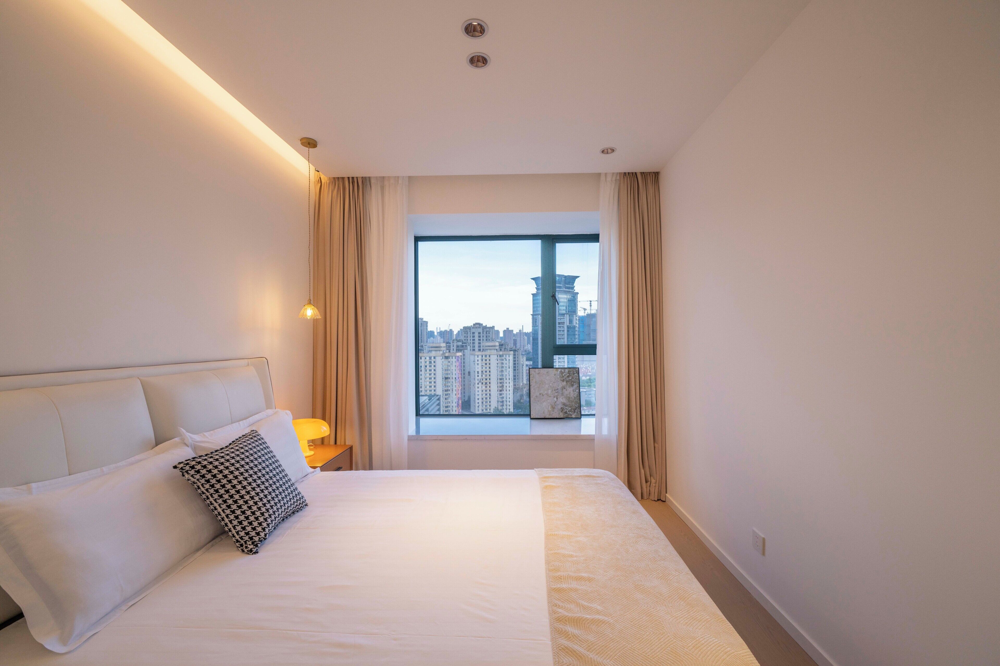 A hotel room with a large bed, a view of the cityscape through a window, and a modern design.