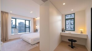 Une chambre d’hôtel moderne, dotée d’un grand lit, d’un bureau et offrant une vue sur le paysage urbain.