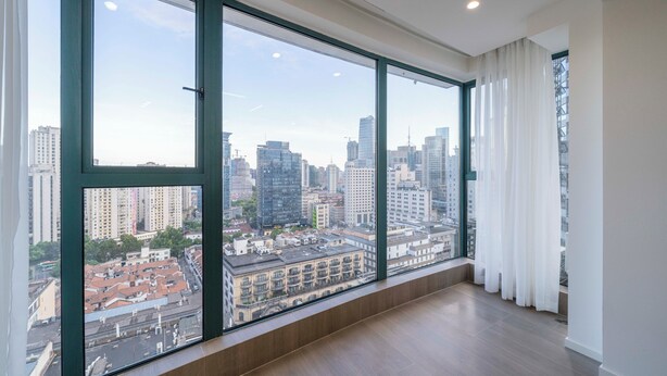 Un appartement situé dans un immeuble de grande hauteur, doté de grandes fenêtres du sol au plafond qui offrent une vue panoramique sur la ville.
