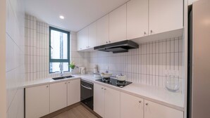 Une cuisine moderne avec des meubles blancs, une cuisinière encastrée et une fenêtre qui laisse entrer la lumière naturelle.