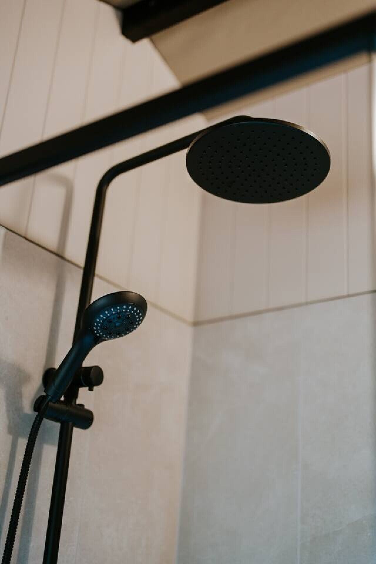 A showerhead with a curved design and a handheld shower attachment.