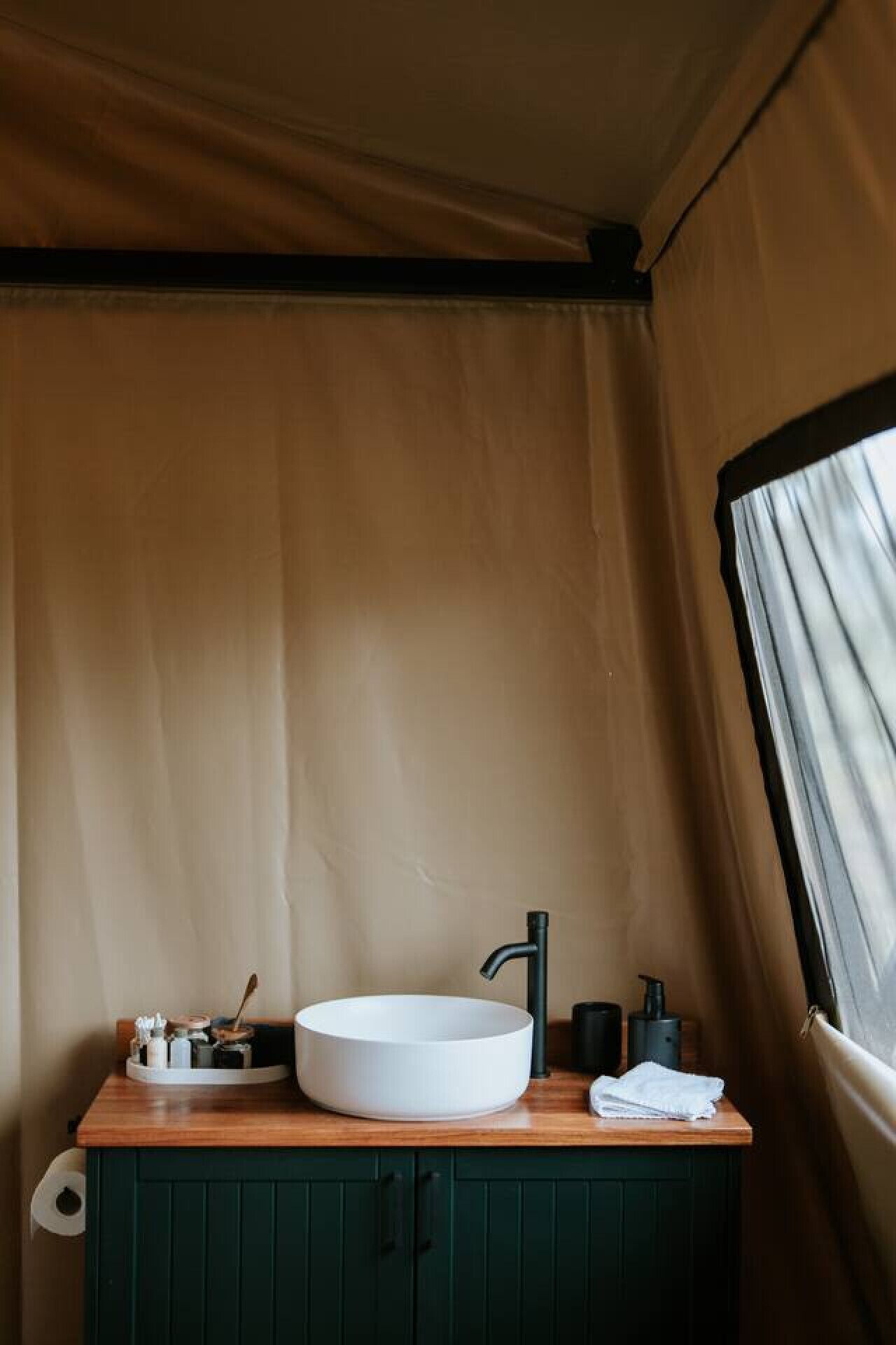 Une salle de bain moderne et compacte, dotée d’un lavabo rond blanc, d’un robinet foncé et d’un meuble-lavabo en bois.