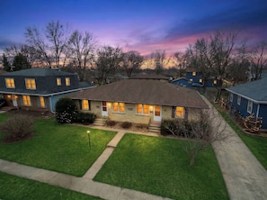 A residential house with a front porch, a well-maintained lawn, and a driveway.