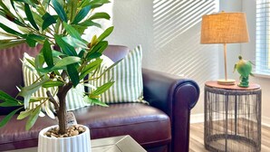 A living room with a potted plant on a coffee table, a sofa, a lamp, and framed artwork on the wall. - Wonderful apartment 10 minutes from Disney (Kissimmee)