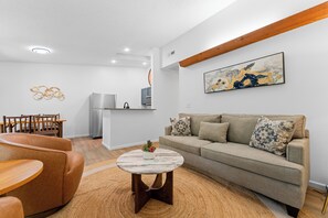 Ein modernes Wohnzimmer mit einer Couch, einem Couchtisch und einem Essbereich mit Stühlen.