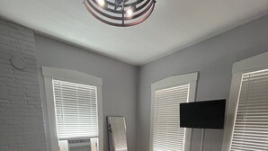 A bedroom with a bed, a TV mounted on the wall, and a ceiling fan. - Historic Alton duplex! Upper unit (Alton)