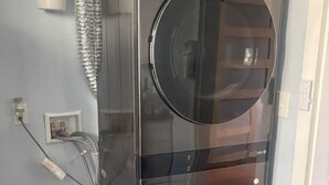 A compact, modern laundry room with two large, black washing machines, a hose, and a water heater. - Historic Alton duplex! Upper unit (Alton)