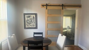 A dining area with a round table, two chairs, a framed picture, and a sliding door leading to another room. - Historic Alton duplex! Upper unit (Alton)