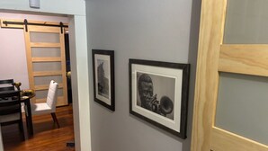 A hallway with framed artwork on the wall, a wooden door, and a dining area with a chair and table. - Historic Alton duplex! Upper unit (Alton)