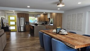 Eine moderne Küche mit Holzschränken, einem Edelstahlkühlschrank und einer Holztischinsel mit blauer Sitzgelegenheit.