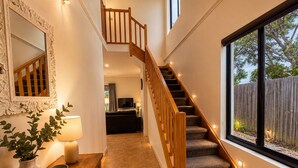 Una escalera con barandillas de madera y peldaños alfombrados que sube a un segundo piso.