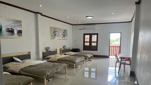 Une chambre d’hôtel avec quatre lits simples, une petite table et un balcon doté d’une rambarde.