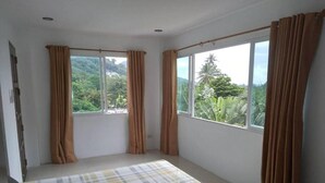 A room with a bed, large windows, and curtains.