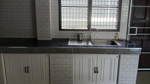 A kitchen with a window, white tiled backsplash, and a stainless steel sink.