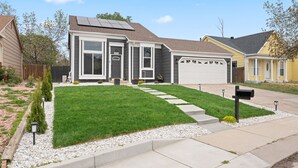 A two-story house with a front yard, a garage, and solar panels on the roof.