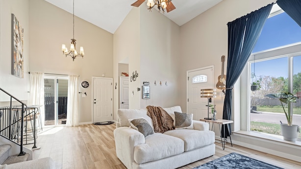 A spacious living room with a large window, a ceiling fan, and a light fixture.