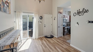A spacious living area with a dining table, a chandelier, and a sliding glass door leading to a patio.