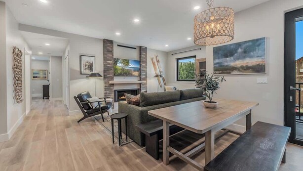 Una sala moderna con chimenea, una mesa de comedor y un ventanal grande.