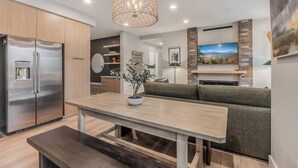 Una cocina moderna con refrigerador integrado, una mesa de comedor y un banco. Hay un ventanal con vistas al exterior.