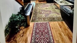 Un salon spacieux avec un escalier en bois, un ventilateur de plafond, un ensemble de canapés et un tapis à motifs.