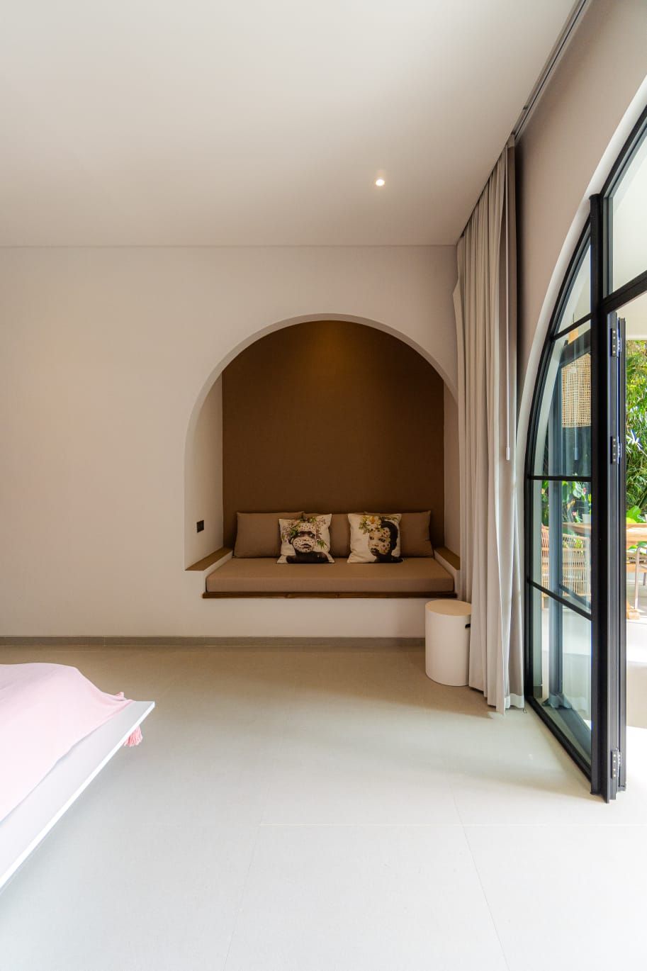 A modern room with a built-in bench against a wall, a large window with curtains, and a clean, minimalist design.