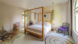 A spacious bedroom with a four-poster bed, a small round table, two chairs, and a large window providing natural light. - Villa Sungai (Cepaka)