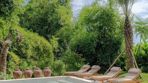 A pool with lounge chairs and decorative vases. - Villa Sungai (Cepaka)