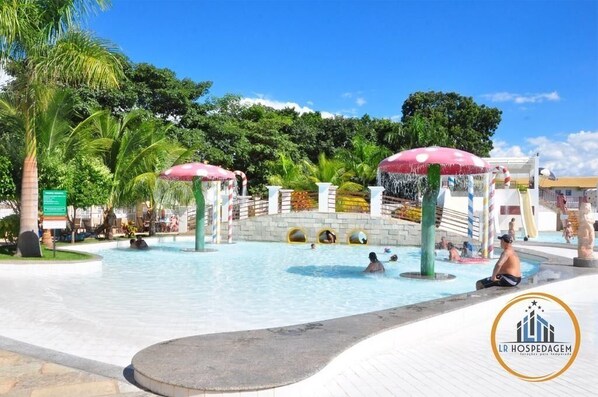 A swimming pool area with multiple water features, including a water slide and several small pools.