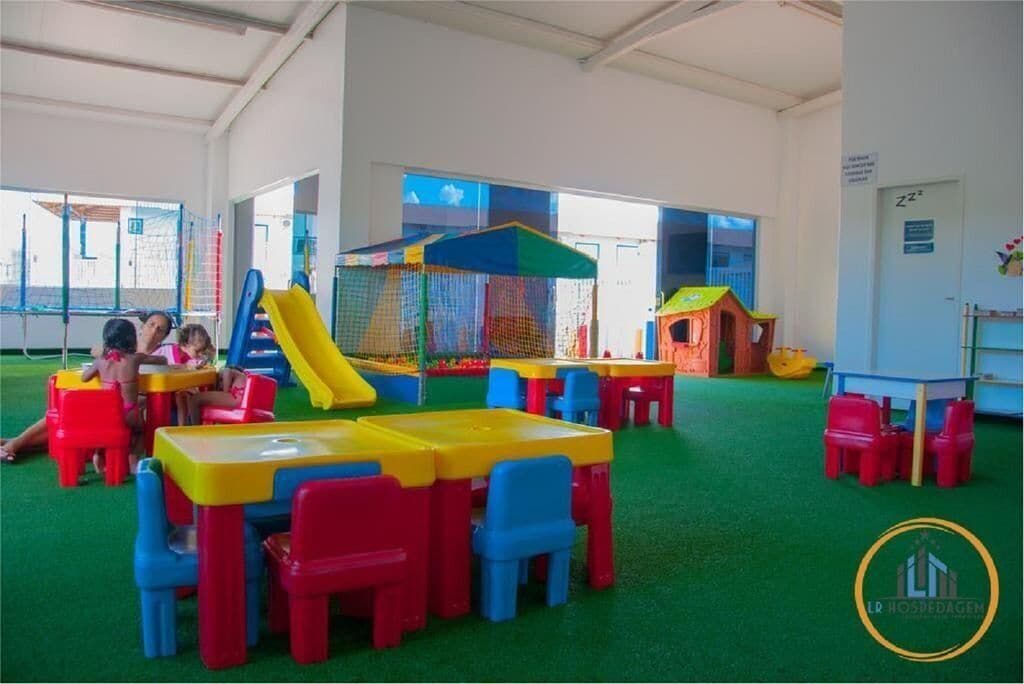 A children's play area with colorful tables and chairs, a slide, and a playhouse.