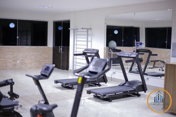 Un gimnasio con cintas de correr, elípticas y una bicicleta estática.