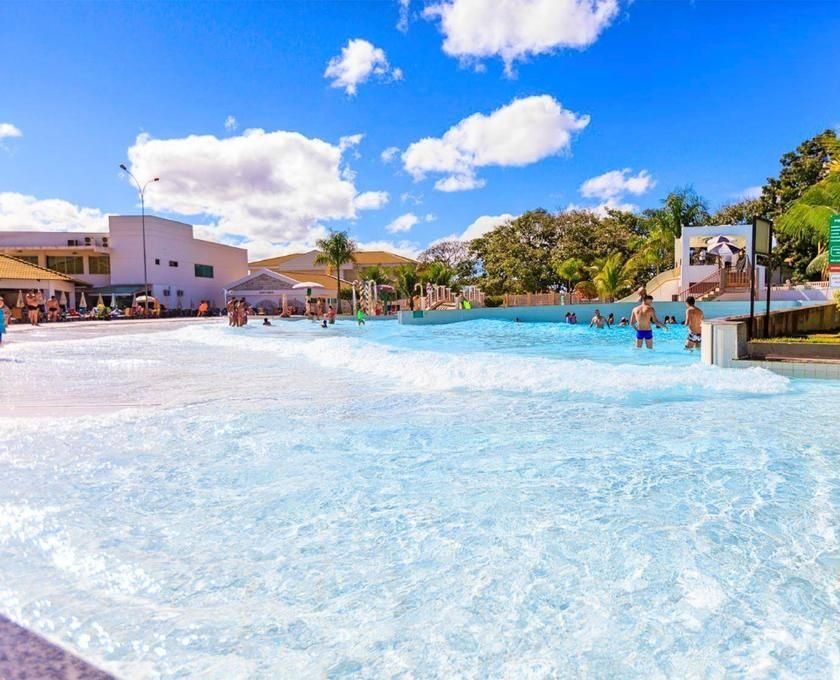 A pool area with clear blue water, surrounded by buildings and palm trees.
