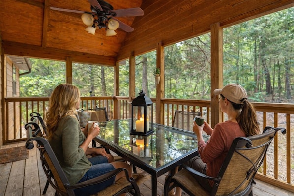 A covered outdoor area with a glass table, two chairs, and a lantern.